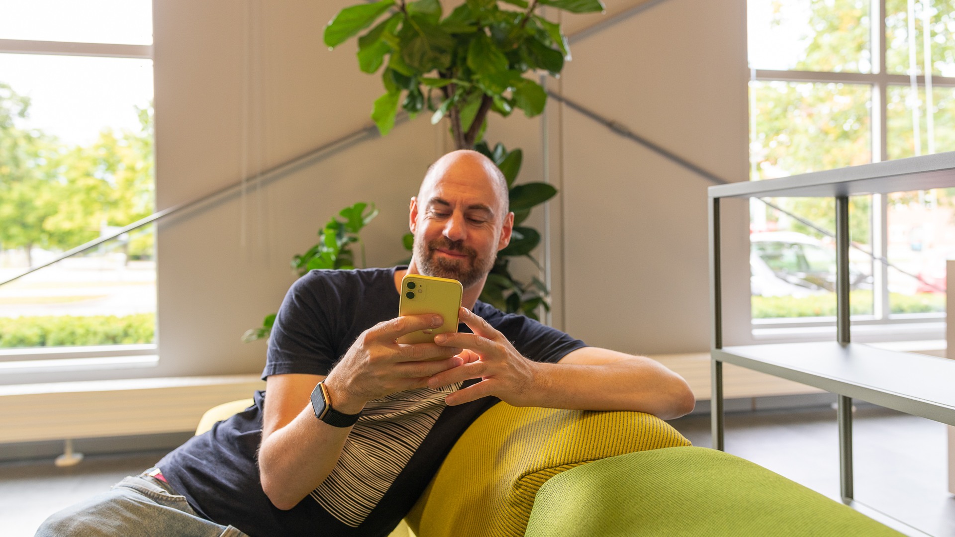 En man sitter i en soffa och scrollar på sin mobil.